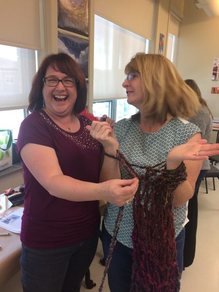 Michelle, Director of Corporate Services, teaches Karen, Director of Property Development how to arm knit.